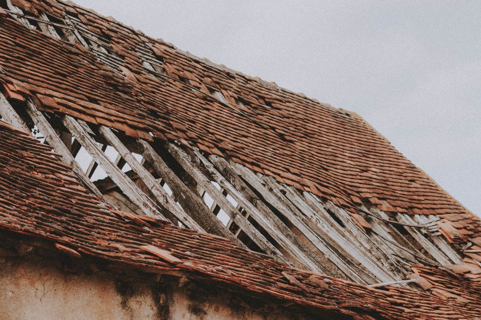 Close-up of a deteriorated roof with missing covering and exposed timbers.