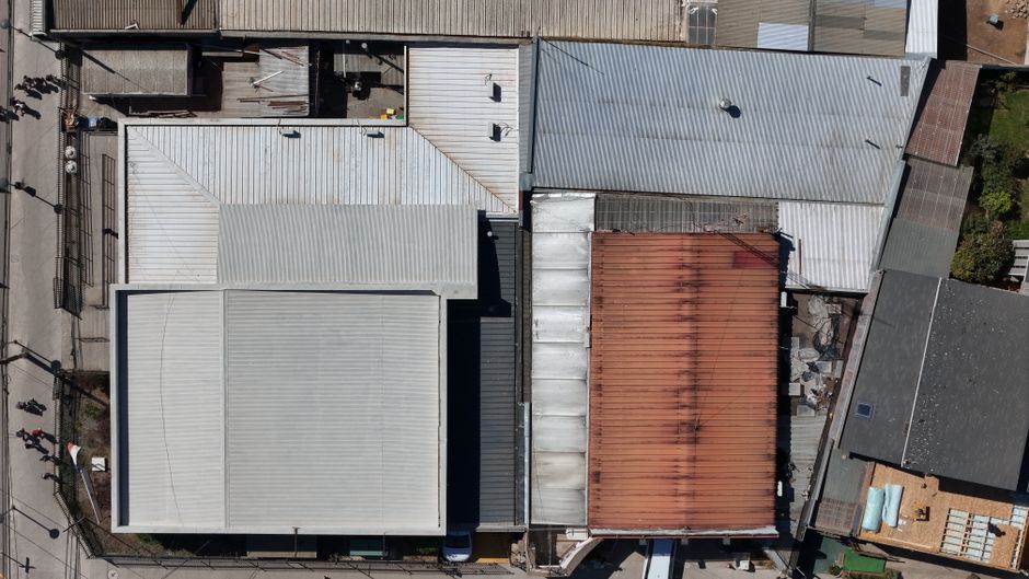 Aerial view of large industrial warehouse roofs with different surfaces.